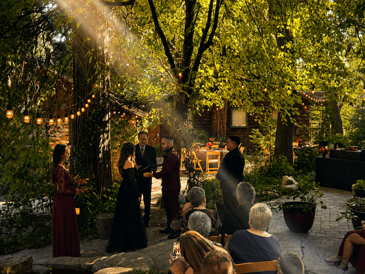 Late afternoon sunlight falling through the pines onto a wedding ceremony at Willow Woods Park
